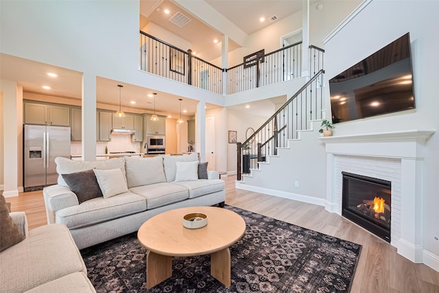 21031 Secretariat Meadow Ln, Tomball, TX 77377 - living area featuring light wood-style flooring, a high ceiling, a glass covered fireplace, and recessed lighting