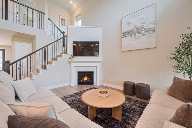 21031 Secretariat Meadow Ln, Tomball, TX 77377 - living room featuring wood finished floors, a towering ceiling, a tile fireplace, and stairs