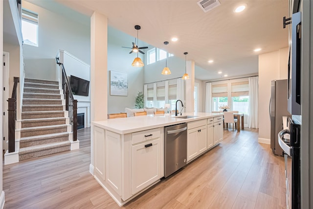 21031 Secretariat Meadow Ln, Tomball, TX 77377 - kitchen with appliances with stainless steel finishes, a ceiling fan, white cabinetry, a center island with sink, and light wood-style flooring