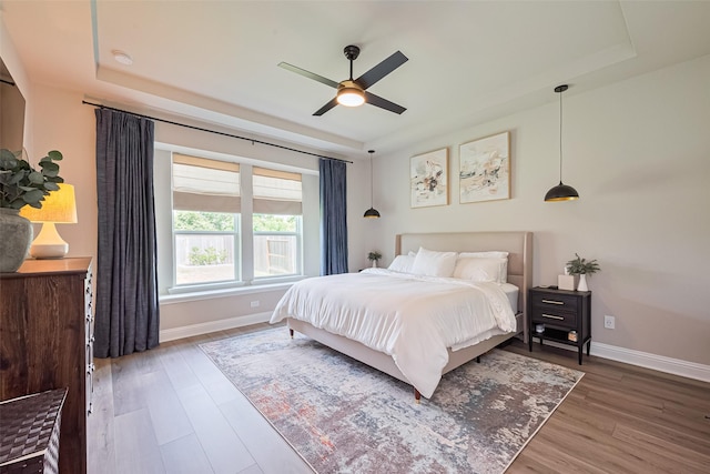 21031 Secretariat Meadow Ln, Tomball, TX 77377 - bedroom featuring a tray ceiling, wood finished floors, and a ceiling fan
