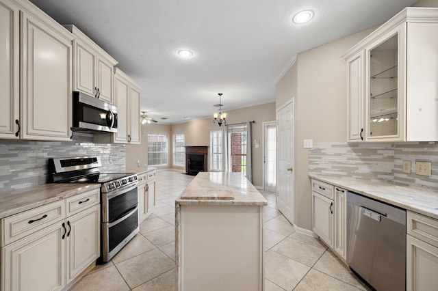 5411 Davids Bend Dr, Sugar Land, TX 77479 - kitchen with stainless steel appliances, a center island, decorative backsplash, a fireplace, and crown molding
