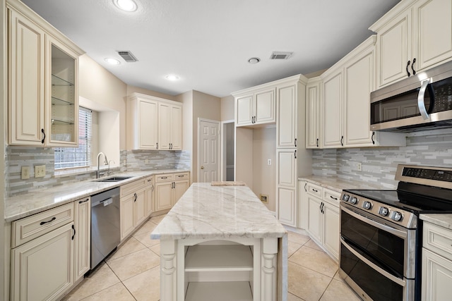 5411 Davids Bend Dr, Sugar Land, TX 77479 - kitchen featuring stainless steel appliances, decorative backsplash, light stone countertops, light tile patterned flooring, and cream cabinetry