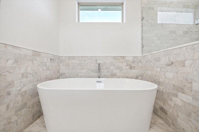 1609 Roy St, Houston, TX 77007 - bathroom with tile walls, a soaking tub, wainscoting, and marble look tiles