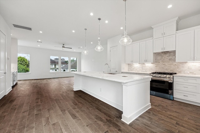 1609 Roy St, Houston, TX 77007 - kitchen featuring stainless steel range with gas stovetop, recessed lighting, open floor plan, decorative backsplash, and an island with sink