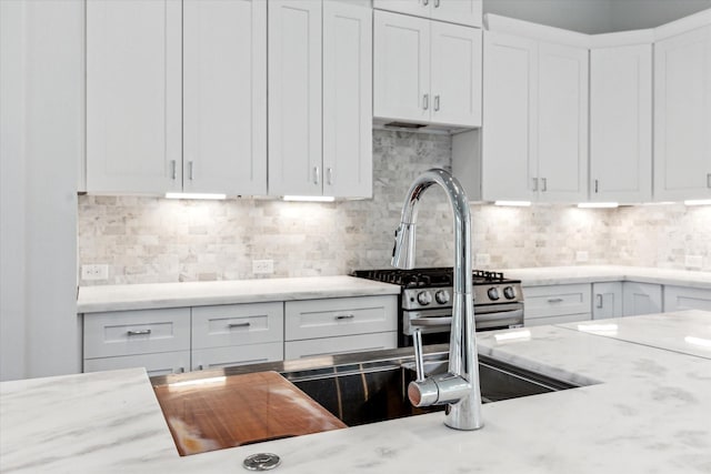 1609 Roy St, Houston, TX 77007 - kitchen featuring light stone countertops, white cabinetry, tasteful backsplash, and gas stove