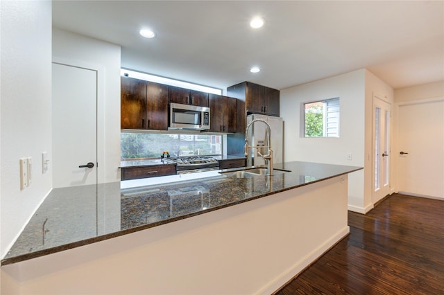 2902 Commerce St, Houston, TX 77003 - kitchen featuring appliances with stainless steel finishes, dark wood-style flooring, dark brown cabinets, recessed lighting, and dark stone counters