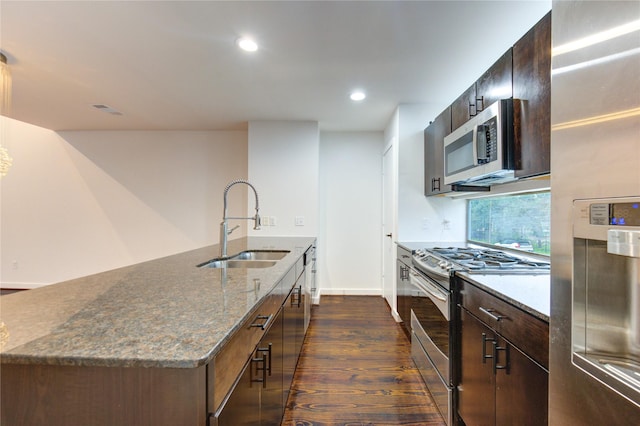 2902 Commerce St, Houston, TX 77003 - kitchen with appliances with stainless steel finishes, dark wood-style flooring, a kitchen island with sink, recessed lighting, and dark stone countertops