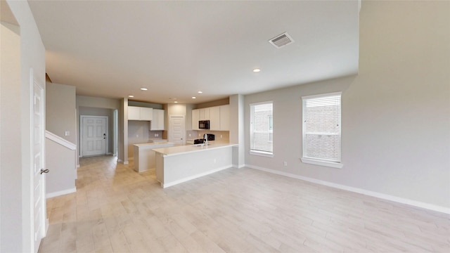 333 Spruce Oak Ln, Waller, TX 77484 - kitchen with black microwave, light wood finished floors, white cabinets, a peninsula, and recessed lighting