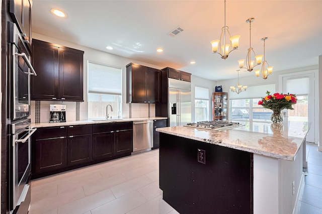 18806 Dove Creek Springs Trl, Cypress, TX 77433 - kitchen with appliances with stainless steel finishes, a chandelier, light stone counters, a center island, and decorative light fixtures