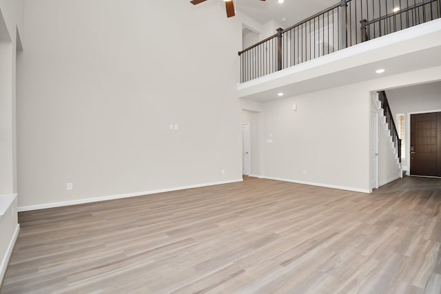22006 Big Sky Dr, Tomball, TX 77375 - unfurnished living room featuring a ceiling fan, a high ceiling, stairs, light wood-style flooring, and recessed lighting