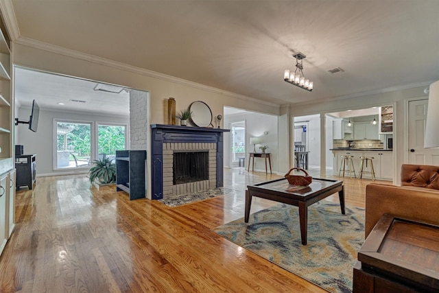 6103 Allentown Dr, Spring, TX 77389 - living room featuring ornamental molding, a brick fireplace, wood finished floors, and a chandelier