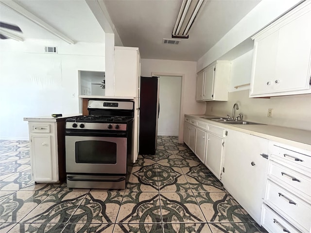 12332 Kayla Ln, Houston, TX 77015 - kitchen featuring gas stove, freestanding refrigerator, light countertops, and white cabinets