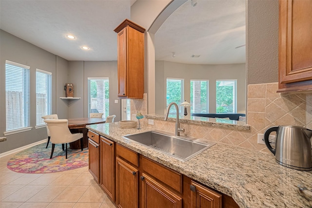 8812 Snowy Owl Loop, Missouri City, TX 77459 - kitchen with tasteful backsplash, brown cabinetry, arched walkways, light tile patterned flooring, and recessed lighting