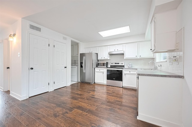 10174 Beekman Place Dr, Houston, TX 77043 - kitchen with stainless steel appliances, washer / dryer, a skylight, dark wood-type flooring, and white cabinets