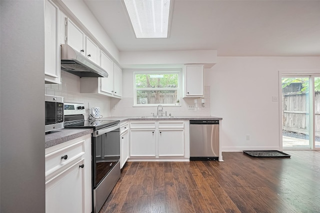 10174 Beekman Place Dr, Houston, TX 77043 - kitchen featuring appliances with stainless steel finishes, under cabinet range hood, dark wood-style flooring, tasteful backsplash, and plenty of natural light