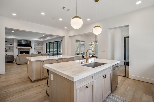 4991 Dumfries Dr, Houston, TX 77096 - kitchen featuring a kitchen island with sink, a lit fireplace, light wood-style floors, recessed lighting, and dishwasher