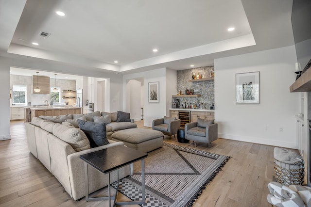 4991 Dumfries Dr, Houston, TX 77096 - living room featuring a tray ceiling, a bar, light wood-style floors, recessed lighting, and beverage cooler