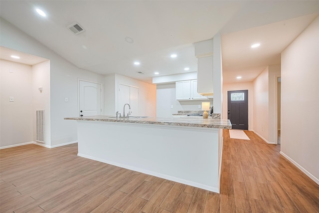 19718 Franz Rd, Houston, TX 77084 - kitchen featuring light wood finished floors, white cabinets, recessed lighting, light stone countertops, and a peninsula