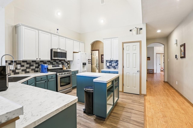 3211 Waterglen Ct, League City, TX 77573 - kitchen with appliances with stainless steel finishes, arched walkways, backsplash, light countertops, and recessed lighting
