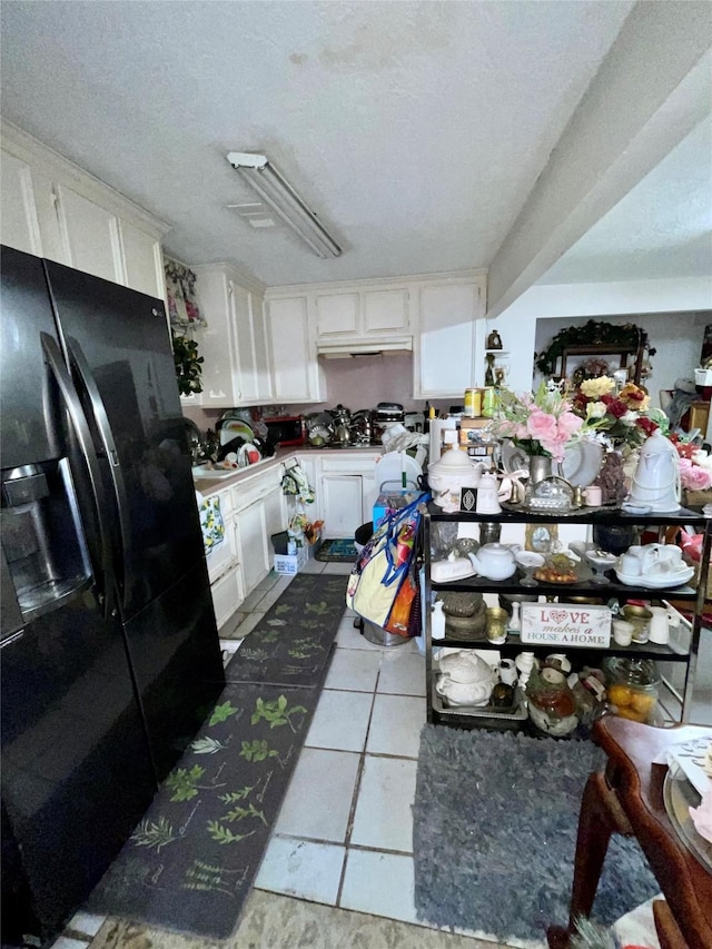 1107 Wooding St, Houston, TX 77011 - kitchen featuring black fridge with ice dispenser, white cabinets, tile patterned floors, and a textured ceiling