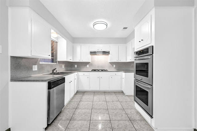 619 Rocky Mountain Dr, Houston, TX 77037 - kitchen with stainless steel appliances, under cabinet range hood, tasteful backsplash, and white cabinetry