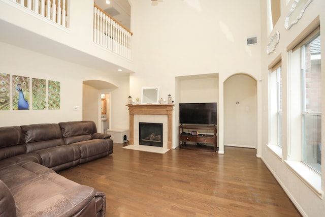 14310 Saint Pierre Ln, Cypress, TX 77429 - living room featuring arched walkways, wood finished floors, a towering ceiling, and a fireplace with flush hearth