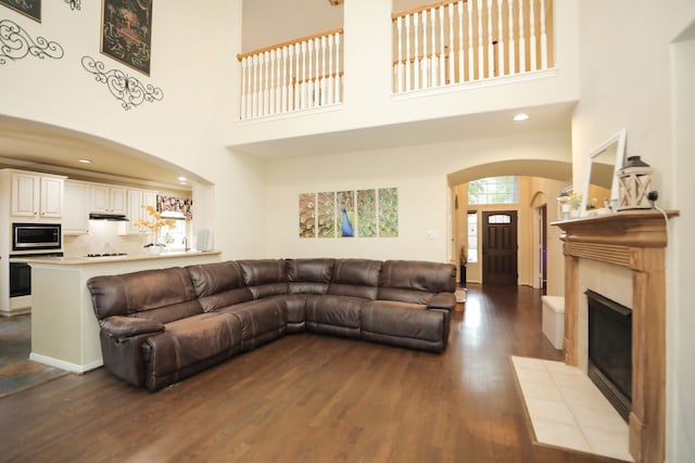 14310 Saint Pierre Ln, Cypress, TX 77429 - living room with arched walkways, dark wood-style flooring, a towering ceiling, a fireplace, and recessed lighting