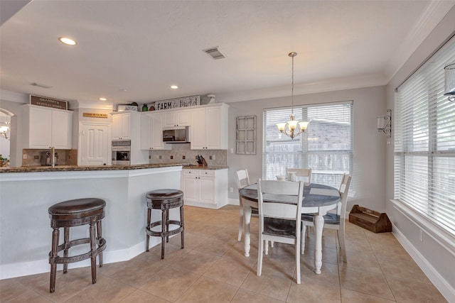 16407 Torry View Ter, Houston, TX 77095 - kitchen with a chandelier, decorative backsplash, crown molding, stainless steel oven, and white cabinetry