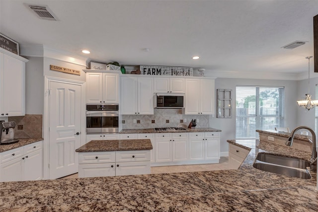 16407 Torry View Ter, Houston, TX 77095 - kitchen featuring appliances with stainless steel finishes, ornamental molding, tasteful backsplash, white cabinetry, and a chandelier