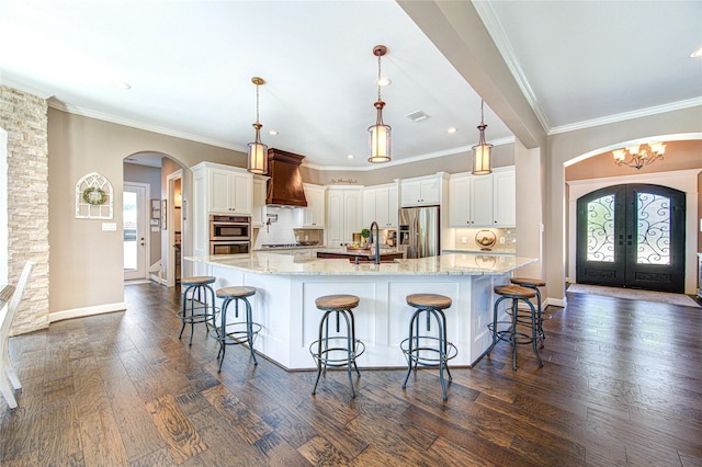 6506 Camillia Ct, Katy, TX 77493 - kitchen featuring arched walkways, stainless steel appliances, french doors, custom range hood, and healthy amount of natural light