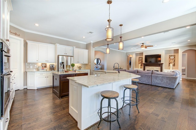 6506 Camillia Ct, Katy, TX 77493 - kitchen featuring arched walkways, stainless steel fridge, a large island with sink, crown molding, and a kitchen bar