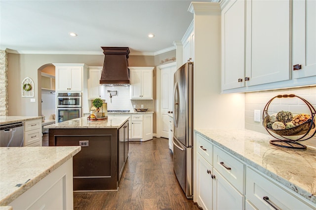 6506 Camillia Ct, Katy, TX 77493 - kitchen with appliances with stainless steel finishes, premium range hood, tasteful backsplash, white cabinets, and dark wood-style flooring