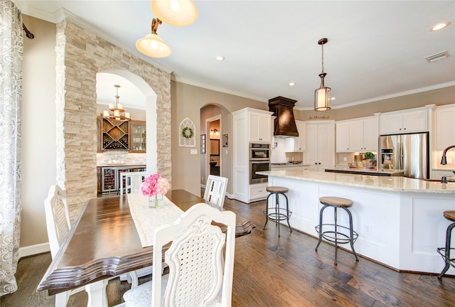6506 Camillia Ct, Katy, TX 77493 - dining space featuring dark wood-style floors, crown molding, arched walkways, recessed lighting, and beverage cooler