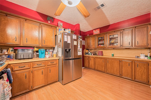 16318 Spinnaker Dr, Crosby, TX 77532 - kitchen with stainless steel fridge with ice dispenser, brown cabinets, and a textured ceiling