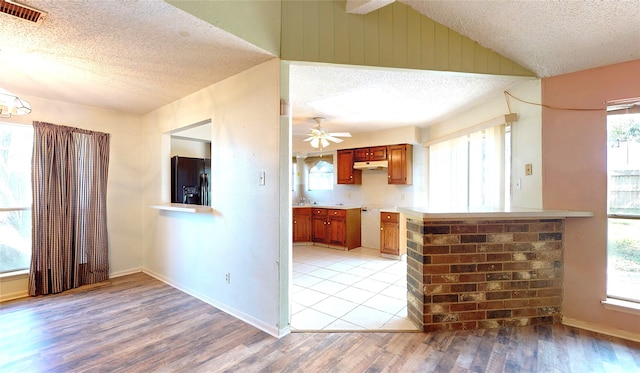 1116 N Bristol Ct, League City, TX 77573 - kitchen with black fridge with ice dispenser, a textured ceiling, brown cabinets, light wood finished floors, and healthy amount of natural light