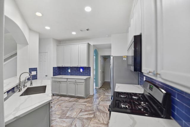 8207 Miramar Crest Ct, Tomball, TX 77375 - kitchen with stainless steel appliances, arched walkways, decorative backsplash, recessed lighting, and light stone countertops