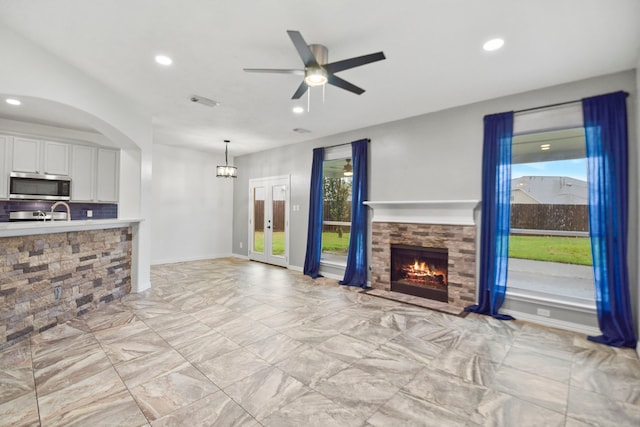 8207 Miramar Crest Ct, Tomball, TX 77375 - unfurnished living room featuring recessed lighting, a stone fireplace, ceiling fan, light marble finish floors, and a chandelier