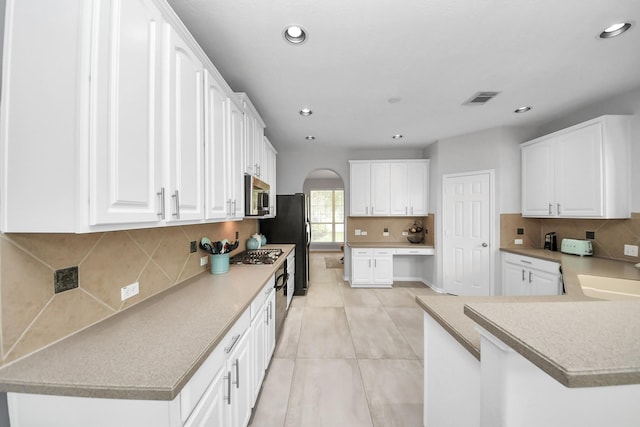 13710 Breezy Meadow Ct, Houston, TX 77044 - kitchen featuring stainless steel microwave, arched walkways, white cabinets, and recessed lighting