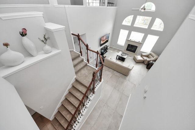 13710 Breezy Meadow Ct, Houston, TX 77044 - stairs with healthy amount of natural light, a towering ceiling, ceiling fan, a glass covered fireplace, and tile patterned flooring