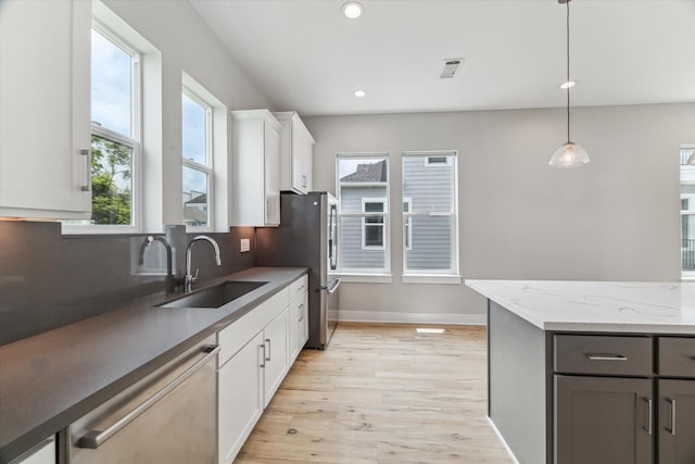 919 W 16th St Unit C, Houston, TX 77008 - kitchen with stainless steel appliances, light wood-type flooring, white cabinetry, pendant lighting, and decorative backsplash