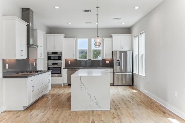 919 W 16th St Unit C, Houston, TX 77008 - kitchen featuring appliances with stainless steel finishes, wall chimney exhaust hood, decorative backsplash, a kitchen island, and recessed lighting