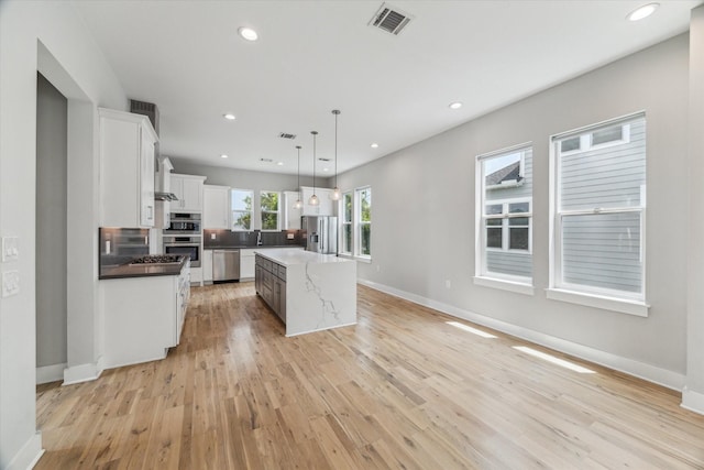 919 W 16th St Unit C, Houston, TX 77008 - kitchen with appliances with stainless steel finishes, light wood-style flooring, a kitchen island, white cabinetry, and decorative light fixtures