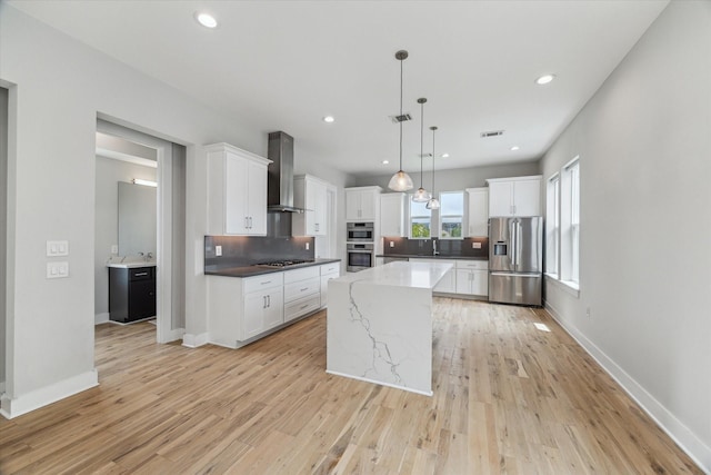919 W 16th St Unit C, Houston, TX 77008 - kitchen with appliances with stainless steel finishes, wall chimney range hood, white cabinets, a kitchen island, and recessed lighting