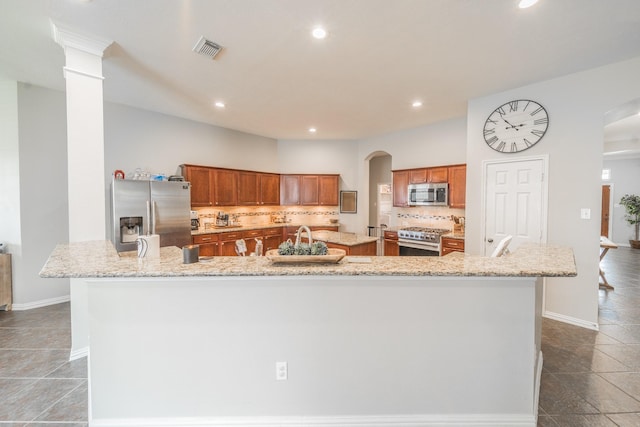 18403 Sierra Falls Ct, Tomball, TX 77377 - kitchen with stainless steel appliances, a large island, backsplash, brown cabinetry, and recessed lighting
