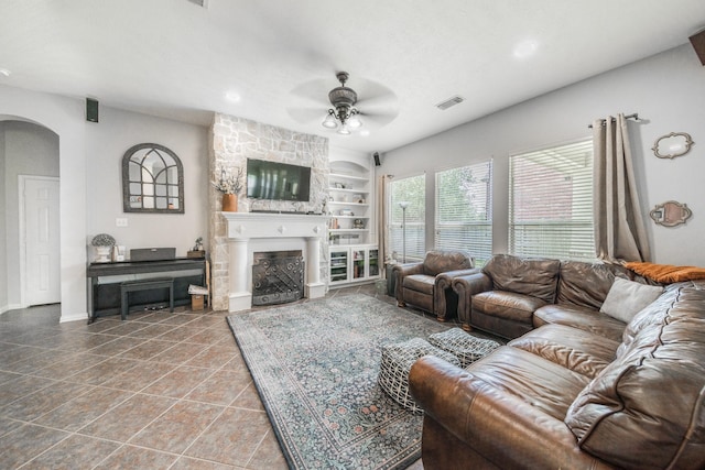 18403 Sierra Falls Ct, Tomball, TX 77377 - living area featuring a ceiling fan, arched walkways, built in features, a fireplace, and tile patterned floors
