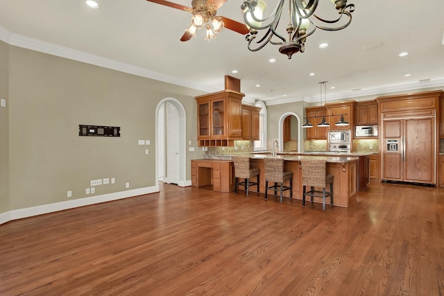 13714 Gainesway Dr, Cypress, TX 77429 - kitchen with built in appliances, brown cabinetry, arched walkways, ornamental molding, and recessed lighting