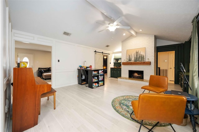 3618 Coltwood Dr, Spring, TX 77388 - living room with a barn door, ceiling fan, a fireplace, a decorative wall, and light wood-style floors