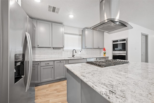 10011 Cliffwood Dr, Houston, TX 77035 - kitchen with stainless steel appliances, island range hood, gray cabinets, light wood-type flooring, and backsplash