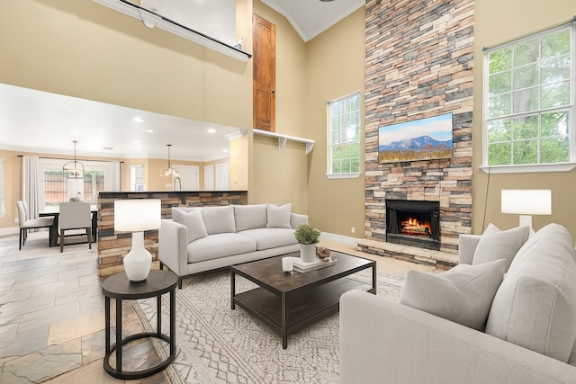 600 Crystal River Rd, Conroe, TX 77316 - living room featuring plenty of natural light, a stone fireplace, crown molding, a towering ceiling, and stone tile floors