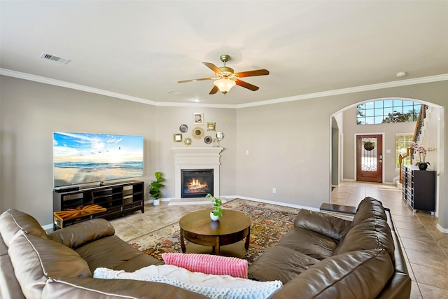 12106 Coldwater Cove Ln, Cypress, TX 77433 - living room featuring arched walkways, light tile patterned flooring, ornamental molding, ceiling fan, and a glass covered fireplace